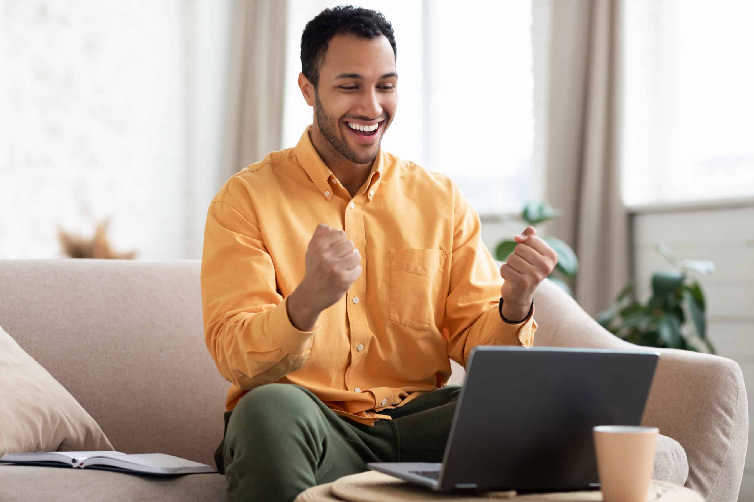 Excited man using laptop after getting approved for a medical marijuana card with Leafy DOC