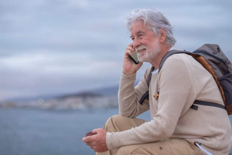 smiling senior man sitting on the cliff in sea getting a medical marijuana card