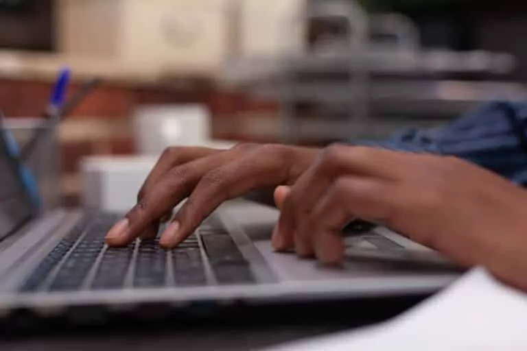 closeup of african american hands typing business data on portable computer keyboard getting medical marijuana card